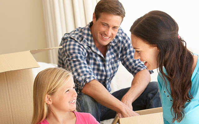 Family Moving Into New Home Surrounded By Packing Boxes