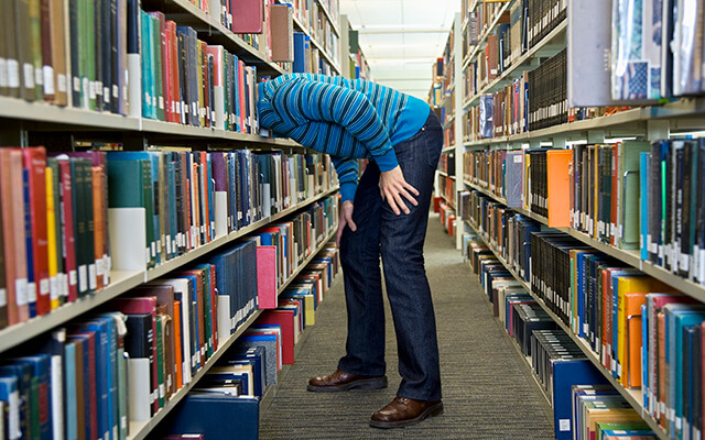 man putting his head in a bookshelf